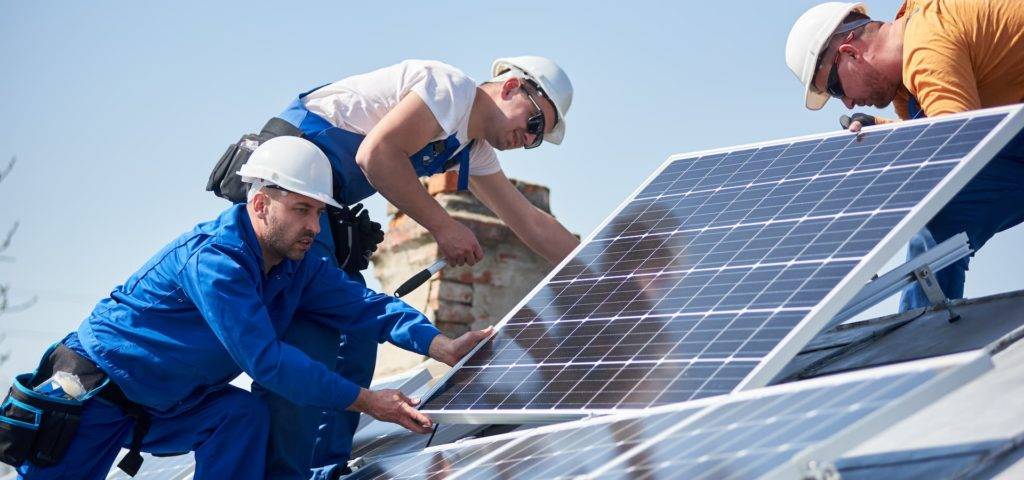 A team of men installing solar panels on a roof
